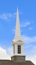 Vertical White steeple on top of the pitched roof of a church with brick exterior wall Royalty Free Stock Photo