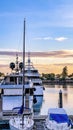 Vertical white yacht boats and sailboats in private dock, pier, gradient orange sky at sunset