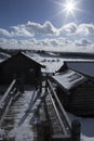 Vertical winter snow shot of old traditional russian wooden houses and rooftops covered in snow with a frozen sea, blue sky, white Royalty Free Stock Photo