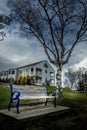 Vertical of a wooden bench against a house in New England, Maine on a cloudy day Royalty Free Stock Photo