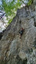 VERTICAL: Young athletic woman top rope climbs up challenging cliff in Slovenia.