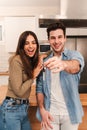 Vertical Young caucasian couple happy to show the keys of their new home looking at camera together, Smiling husband and