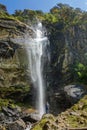 VERTICAL: Young Caucasian man hiking in Tibet poses by the stunning waterfall.