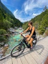 VERTICAL: Young Caucasian woman cycling in Bovec stops to observe the Soca river