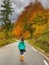 VERTICAL: Young female photographer stands in the middle of a forest road.