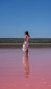 Vertical of a young female in a white dress standing in Pink Lake in Port Gregory, Australia