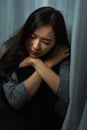 Vertical young woman sitting sad at sunshade, depression emotion on face, looking down in dark room, Portrait of young beautiful Royalty Free Stock Photo