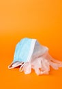 Verticl shot of disposable facemask and gloves isolated on orange background Royalty Free Stock Photo