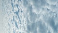 Vertival video. White altocumulus clouds in the rays of the morning sun. The movement of fluffy clouds crossing the blue sky.