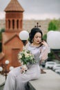 Very attractive bridesmaid sitting in front of the armenian apostolic church, holding bridal bouquet and posing for Royalty Free Stock Photo