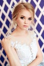 Very beautiful blonde with blue eyes in white bride dress on purple background in studio Royalty Free Stock Photo