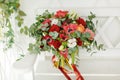 Very beautiful bright bridal bouquet with red flowers, stands on a white bench Royalty Free Stock Photo