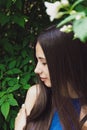 A very beautiful and cheerful girl stands on the street near a bush with white flowers Royalty Free Stock Photo