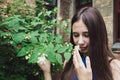 A very beautiful and cheerful girl stands on the street near a bush with white flowers Royalty Free Stock Photo