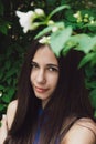 A very beautiful and cheerful girl stands on the street near a bush with white flowers Royalty Free Stock Photo