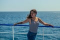 Very beautiful dark-haired woman with a tattoo on her arm in a striped T-shirt and blue denim shorts stands on the deck of a ship Royalty Free Stock Photo