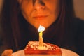 A very beautiful girl blows out a candle on a cake that holds in her delicate hands. Royalty Free Stock Photo