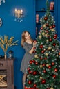 Very beautiful girl stands near the Christmas tree and touches toys. Royalty Free Stock Photo