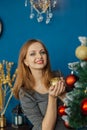 Very beautiful girl stands near the Christmas tree and touches toys. Royalty Free Stock Photo