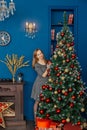 Very beautiful girl stands near the Christmas tree and touches toys. Royalty Free Stock Photo