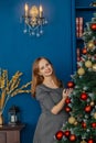 Very beautiful girl stands near the Christmas tree and touches toys. Royalty Free Stock Photo