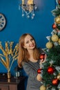 Very beautiful girl stands near the Christmas tree and touches toys. Royalty Free Stock Photo