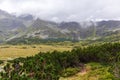 Natural landscape in Polish Tatras with huge gray mountains reaching white clouds and natural turquoise lake in the middle Royalty Free Stock Photo