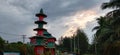 A very beautiful mosque with a very high red green dome and around it there are trees and a clear evening sky