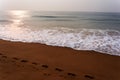 Very beautiful sunrise on the sea beach with foot step on sand and sea water waves and foam under sky in india Royalty Free Stock Photo