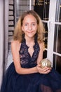 A very beautiful teenage girl in a dress in a New Year`s interior of an apartment or house sits on the windowsill Royalty Free Stock Photo