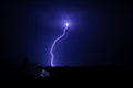 A very branching lightning flashes above the roofs of city houses in a summer thunderstorm. Royalty Free Stock Photo