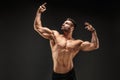 Bodybuilder posing. Fitness muscled man on dark background. Royalty Free Stock Photo