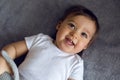 Very cheerful baby boy in white clothes lying on the bed