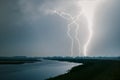 Very close, blinding lightning flash near a lake during a severe thunderstorm