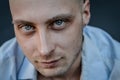 Very close portrait of a young bald man with blue eyes and a blue shirt looking intently at the camera Royalty Free Stock Photo