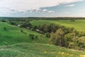 Colorful Bright Sunny Green Field Landscape With Blue Cloudy Sky, River Trees And Hills