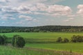 Colorful Bright Sunny Green Field Landscape With Blue Cloudy Sky, Trees And Hills