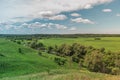 Colorful Bright Summer Sunny Green Field Landscape With Blue Cloudy Sky, River Trees And Hills