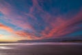 Very colourful sky at dawn with pink and orange colours over a beach in New Zealand