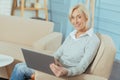 Happy senior woman looking glad while holding a big laptop