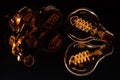 A Very crisp steampunk shot of a pair of goggles and a lit edison lightbulb on a reflective surface. Warm tones and sharp focus