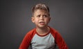 Very cute little boy with angry confused expression on face. Child is upset, sad, focused and serious. Cut out on grey