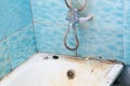 Very dirty bath, shower, water tap and tiles. Heavily soiled white bath tub. Bathtub needs cleaning. Grimy tub. Blue tiles