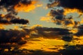 A very dramatic sky full of yellows, blues and oranges. Contrasting clouds during sunset illuminated by the setting sun