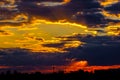 A very dramatic sky full of yellows, blues and oranges. Contrasting clouds during sunset illuminated by the setting sun Royalty Free Stock Photo
