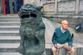 Very elderly European Man with Nordic Walking Sticks and Mythical Chinese Imperial Lion Guard.