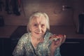 Very elderly woman eating a piece of pizza at home.