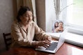 Very elderly woman happily holding a laptop