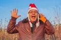 Very emotional man in funny santa hat talking on the phone