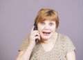 Very emotional woman with gold teeth with the telephone handset on a gray background. Royalty Free Stock Photo